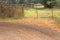 Rusty farm gate with autumn leaves on gravel road