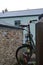 Rusty green bike propped up in a house`s backyard in the rain