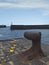 Rusty iron bollard on dock, harbor entrance and port and starboard signals. Nautical, ports and maritime navigation fund