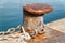 A rusty marine bollard with nautical ropes along the quayside