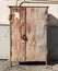 A rusty metal cabinet to cover a gas valve and a locked faucet on a city street