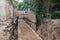 Rusty metal pipes, a wooden fence and a deep pit in the ground