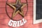 Rusty metal star sign hanging on a wooden wall of a grill place