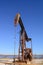 Rusty Oilfield Pumpjack rocking horse over a wellhead. Clear b