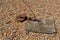 A rusty old shackle on a pebbled beach attached to a rusty chain