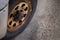 Rusty old truck wheel parked in random area. Oxidized black colored ream set tire. Not so good condition parts of the vehicle. It