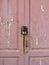 Rusty padlock on pink wooden door with uncorked paint. Old metal padlock on a uncorked wooden door. Old pink door with rusty and