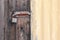 Rusty padlocked bolt on old wooden door and painted corrugated iron shed