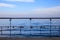 Rusty padlocks has been locked on a peeled railing of platform. Blue sky and sea background.