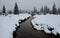 Rusty peat water in a creek in the mountains with snow covered surroundings in the taiga. The peat spring in the mountains feeds s