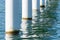 Rusty pier posts in salt sea water. White columns diagonal. Pillars mount for bridge. Sunny weather