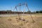 Rusty playground equipment with a swingset sits in a courtyard of an abandoned motel