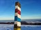 Rusty pole with touristic mark. Blue and red touristic direction sign. Path in winter hills with snow, blue clear sky