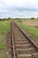 Rusty rail track between meadows