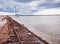 Rusty razy rails and rotten sleepers covered of salt on old railroad tracks on a mound at salt mining lake near brine