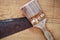 Rusty saw and paintbrush lying on a wooden board