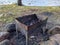 rusty and small barbecue with black burnt coals on the sandy shore