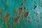 A rusty teal surface, with paint flaking