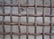 Rusty thick heavy intertwined metal vintage grid surface on wood