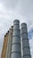 Rusty weatherworn old smokestacks against gray cloudy sky