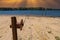 A rusty wench with a long cable in the silky brown sand of the beach on the banks of the rippling lake with lush green trees