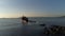 Rusty wrecked ship sunk in a blue sea on blue, cloudy sky and shining sun background. Shot. Crashed boat near sea shore