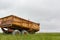 Rusty yellow farm tractor wagon in green landscape