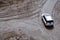 Rutting and white car on a dirt road.