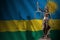 Rwanda flag with statue of lady justice and judicial scales in dark room. Concept of judgement and punishment