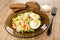 Rye bread, bowl with mayonnaise, plate with vegetable mix, boiled eggs, fork on wooden table