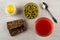 Rye bread with sunflower seeds, salt, bowl with green peas, spoon, glass with tomato juice on table. Top view