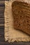 Rye cereal bread on a jute napkin on a dark wooden table