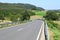 s-curve of an Eifel road through farmland with a tractor on the far end