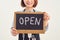 It`s open here. A smiling woman is holding a sign with the inscription