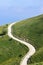 S-shaped country road winding along the slopes of a mountain and disappearing beyond the horizon into the clouds vertical shot