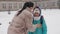 It`s snowing, mom hugs her daughter and walks to school in winter.