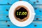 It`s twelve o`clock already. Time to wake up and hurry. An image of a top viewed coffee cup with clocks face showing 12