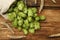 Sack with fresh green hops and wheat ears on wooden table, flat lay