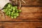 Sack with fresh green hops and wheat ears on wooden table, flat lay. Space for text