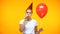 Sad adult woman blowing noisemaker holding balloon, bad mood at birthday party
