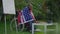 Sad African American man covered with USA flag sitting in wheelchair on summer backyard outdoors thinking. Frustrated