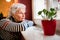 Sad alone senior woman looking through window