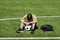 Sad alone teenage boy sitting in empty school sport stadium outdoors. Emotions, defeat, lost game, difficulties