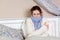 Sad alone young woman in white sweater and blue scarf feeling cold sick and resting home in bed