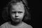 Sad annoyed small kid girl looking up on black background with empty copy space. Closeup studio portrait. Black and white
