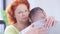 Sad annoyed woman with disgust facial expression hugging man indoors. Close-up face of irritated redhead Caucasian wife