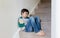 Sad asian boy sitting alone on staircase in the morning, Lonely kid looking dow with sad face not happy to go back to school,