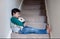 Sad asian boy sitting alone on staircase with teddy bear, Lonely kid looking dow with sad face not happy to go back to school,