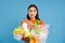 Sad asian female student, holds recycling waste, collects plastic garbage to take it to recycle center, blue background