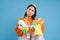 Sad asian woman holding garbage, empty plastic bottles and waste, tired of recycling, sorting rubbish, isolated on blue